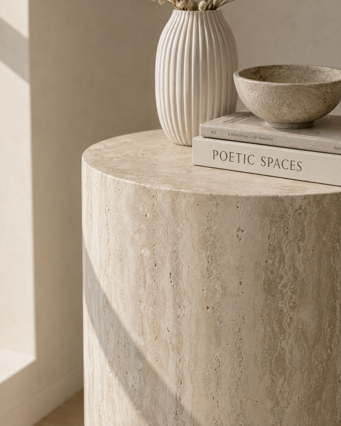 Close-up of ORLO natural travertine pedestal by DEKATO LIVING showing the rounded top edge and vertical stone movement