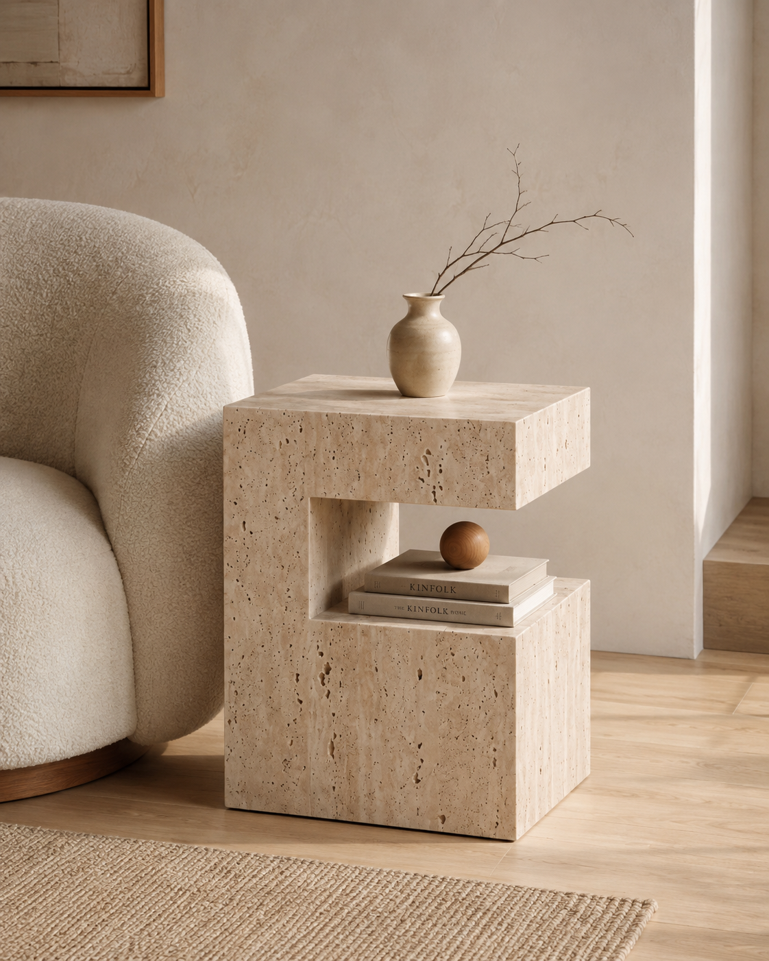 PIETRA natural travertine side table by DEKATO LIVING beside a woman relaxing with coffee in a warm contemporary living room